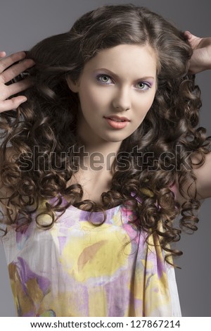 very nice young girl in spring dress with long curly hair looking in camera smiling