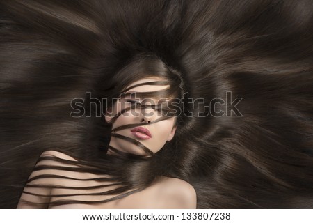 pretty brunette with long  hair laying down and some locks on the face and the neck