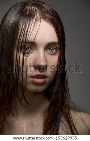pretty clean brunette female with wet skin and hair, water drops on the visage looking in camera with sensual eyes. Close-up portrait