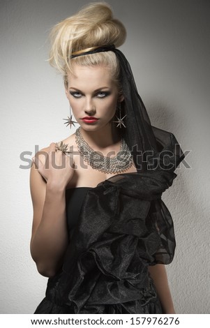 portrait of glamour woman with creative Halloween style, blonde hair-style, dark make-up, sexy dark dress and bright accessories
