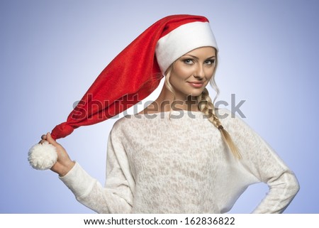 blond girl in white dress with a long christmas hat looking in cameara on blue background