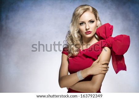 young and sexy beautiful blond woman in red dress with nice hair style and a big bow on shoulder.looking in camera