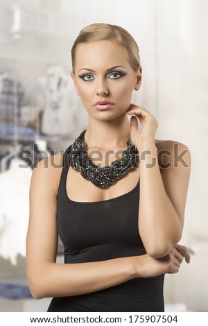 cute young girl with modern elegant style posing with pretty hair-style, cute blue make-up, dark dress and creative beads necklace