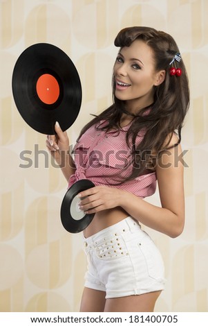 fashion portrait of sexy brunette girl with vintage pin-up style smiling and taking vinyl LP in the hand