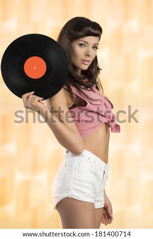 sexy brunette woman wearing like pin-up posing with vinyl music disc in the hand