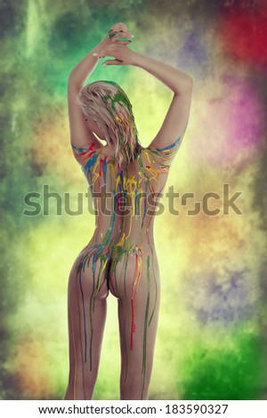 very sensual naked girl with multicolored body paint over her body giving sexy pose against white background.