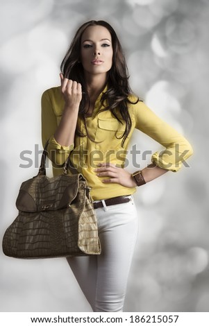 cute brunette woman with fashion casual style posing with yellow shirt, white trousers and big vogue bag