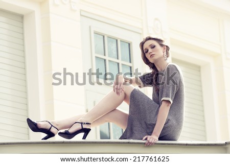 pretty blonde girl with braid hair-style and elegant dress posing in fashion outdoor portrait, wearing pretty jewellery
