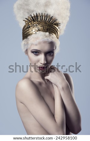 cute creative beauty portrait of sensual naked woman with bizarre hairdo and golden accessories on the head. Stylish make-up