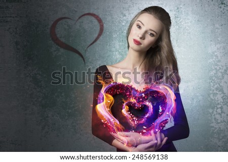 Young, beautiful, romantic valentines girl with curly hairstyle and with valentine heart.She wears black top and brown makeup.