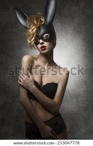 Erotic curly female with sexy lace lingerie posing with bizarre bunny ears in dark ester shoot. Glamour style, perfect body