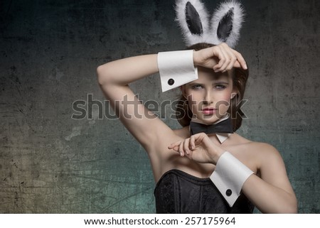 sexy brunette pinup girl with fluffy bunny ears, papillon and dark corset posing in easter glamour portrait