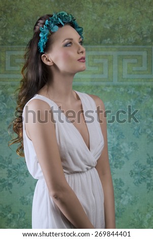 beautiful brunette woman with long wavy hair posing in spring portrait with white dress and flore on the head