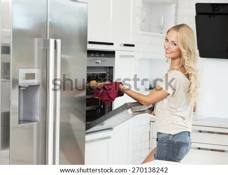 commercial shot of young girl , smiling and cooking with oven , in her luxury kitchen