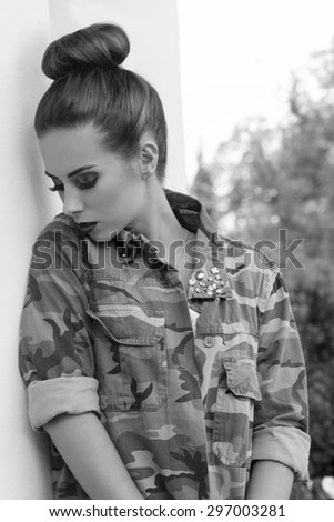 sensual woman posing in outdoor fashion portrait with creative hair-style, rock make-up and streetwear military shirt. In sensual pose , black and white image.