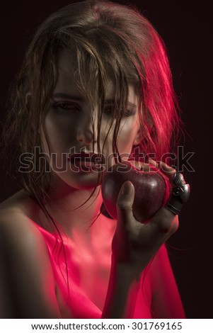 cute girl in half-light close-up portrait with red light. Posing with wet hair, perfect skin and juicy apple in the hand near sensual lips