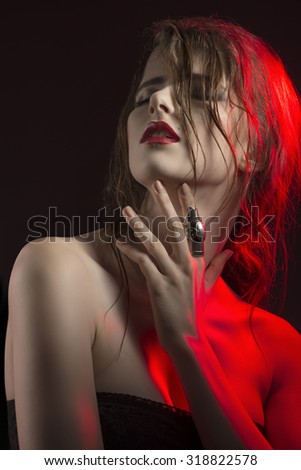 studio portrait in red half-light of sensual woman with wet hair, luxurious lips and cute ring