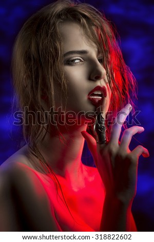 creative close-up portrait of cute woman with erotic expression posing in red light with wet hair, creative ring and sensual lips