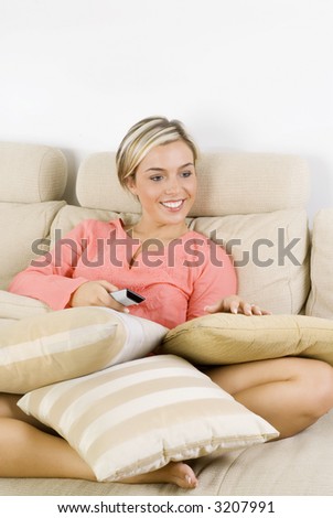 pretty blond female wearing evening pink gown sitting on sofa watching television