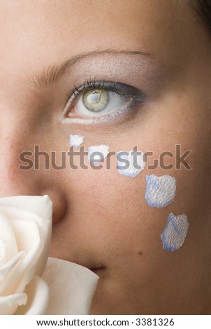 nice portrait of a cute brunette with a white rose and petals painted as tears on her face