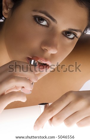 cute and strong eyes brunette putting on her mouth a red lipstick