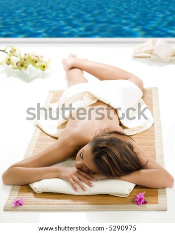 portrait of a beautiful brunette laying down on a wood carpet near a swiming pool