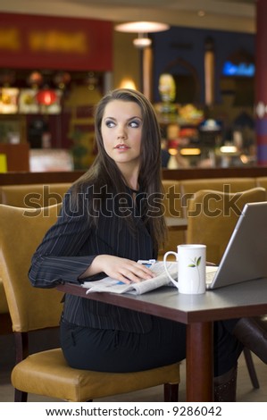 beautiful young woman sitting in a bar with laptop and tea