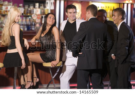 a group of young people sitting near the bar inside a nigh club
