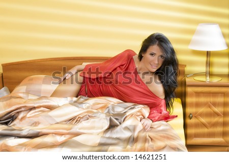 cute young woman laying in bed with sunshine coming through the window curtain
