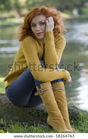 pretty and young woman posing near a river in fall season
