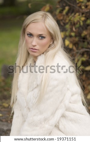 very nice girl wearing a white fur in a winter day in park
