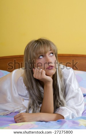 cute blond woman in nightgown sitting on bed with colored sheet