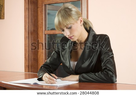 blond girl in front desk of hotel reception writing on a book