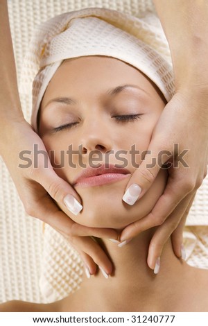 close up of young cute girl getting a massage on her face