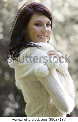 outdoor portrait of a young pretty brunette wearing a white warm sweater