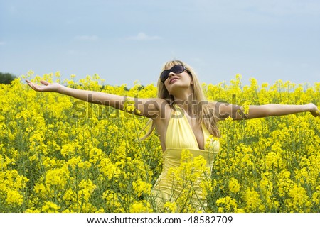 cute young blond woman outdoor in a yellow field wearing sun glasses and a yellow shirt