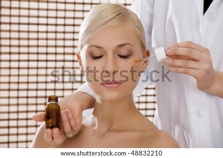 nice advertising shot of a blond girl in act to have a treatment from a nurse in a beauty farm