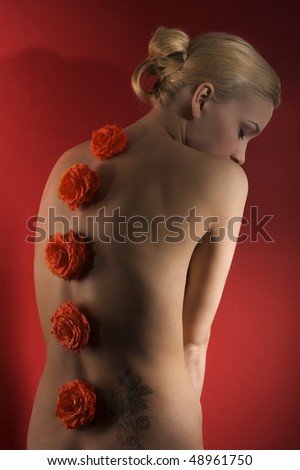 cute blond girl on red background with some flowers on her back taking a pose arching her back
