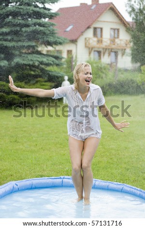 blond girl in a home garden screaming and try to stop a water splatter against her