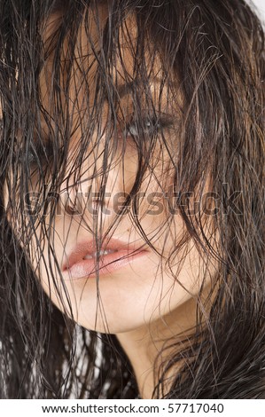 portrait of a cute brunette with wet hair in front of face looking in camera
