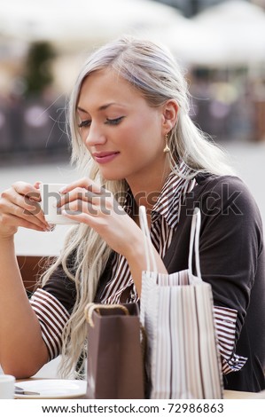 A young woman sitting alone at breakfast table and drinking a tea outdoor