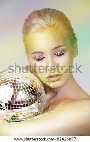 portrait of blond young girl with a mirror shining ball aand some gem stone on eyes as a make up
