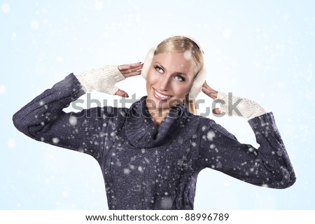 young pretty woman wearing white earmuffs and a blue woolen sweater getting ready for a cold winter day