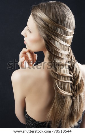 back side portrait of a fashion woman with long hair and old style and creative hairstylish, she is turned at her left and has the left hand near the chin