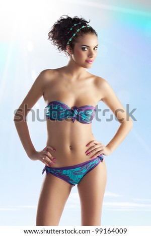 pretty young girl brunette with a stone necklace on hair and a violet and light blue violet bikini swimwear