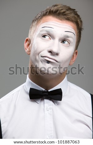 Face mime close-up emotion in thought, a black bow tie, theatrical makeup, isolated on a gray background