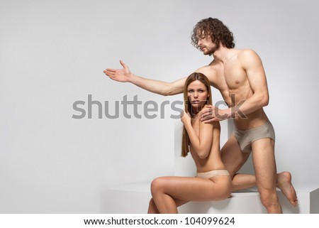 beautiful naked man and woman poziruyutna white cubes