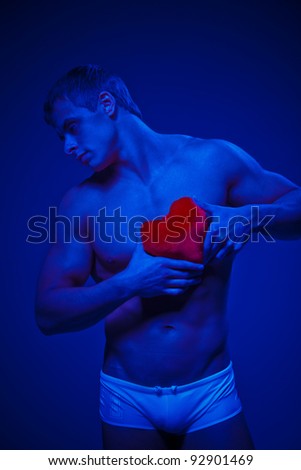 A young strong muscular man with red valentine heart