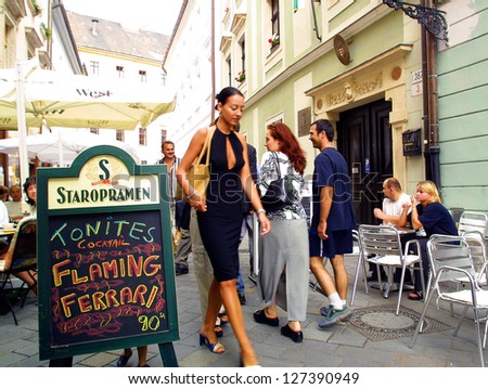 BRATISLAVA - FEBRUARY 1:  An attractive young woman walks past a provocative outdoor sign advertising happy hour at a crowded cafe and bar in Bratislava, Slovakia, on Wednesday, February 1, 2006.