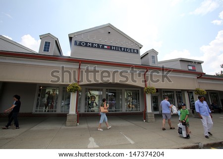 WOODBURY COMMON - JULY 9: Shoppers walk past a Tommy Hilfiger clothing outlet store in Woodbury Common, New York, on Tuesday, July 9, 2013.